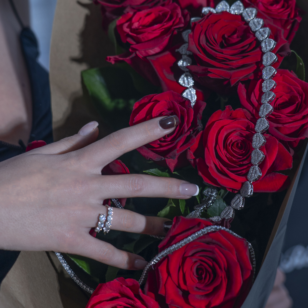 Bague femme sertie de pierres brillantes portée sur la main avec bouquet de roses rouges, style luxe et romantique