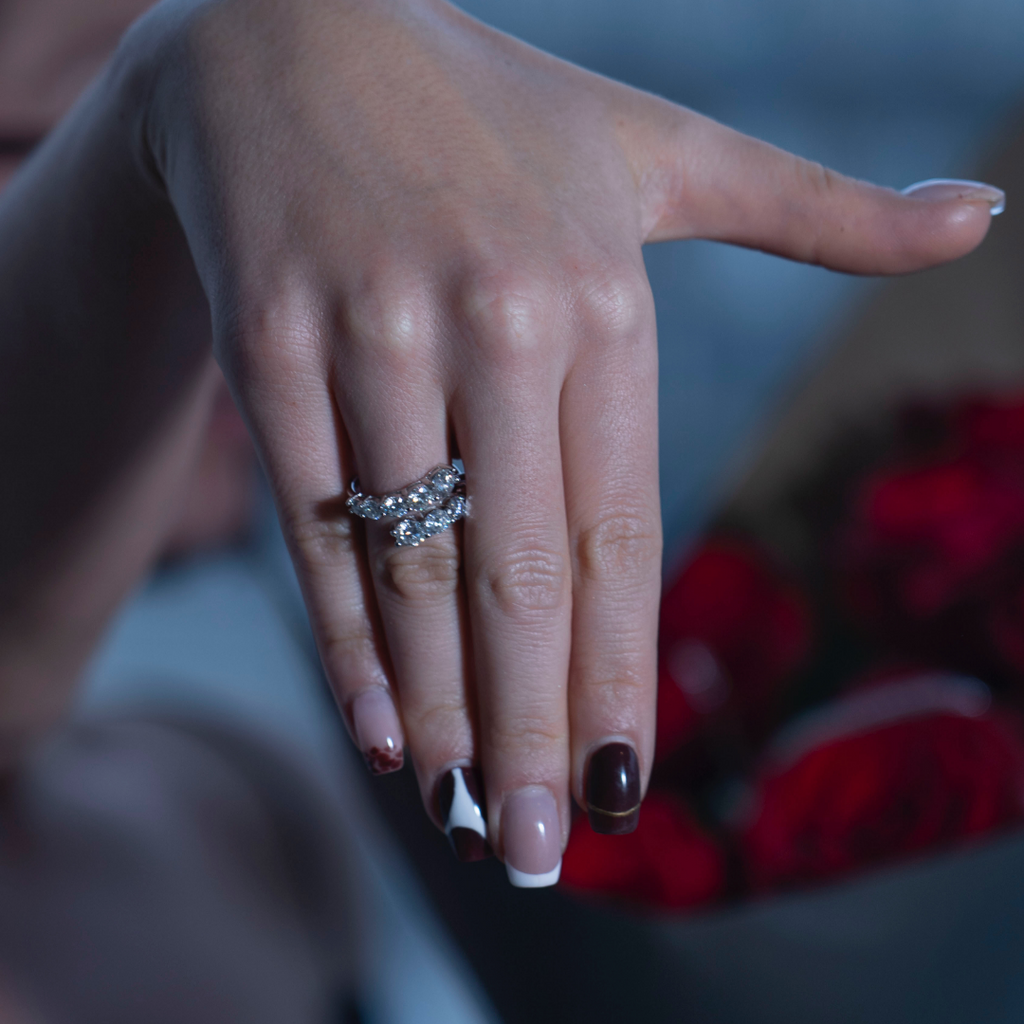 Bague femme sertie de pierres brillantes portée sur la main avec bouquet de roses rouges, style luxe et romantique