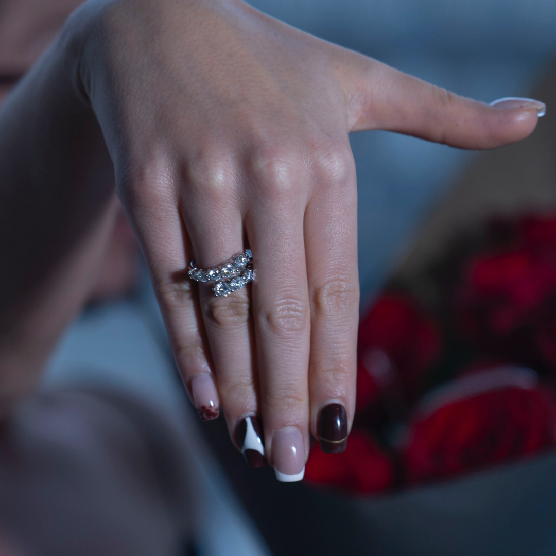 Bague femme sertie de pierres brillantes portée sur la main avec bouquet de roses rouges, style luxe et romantique
