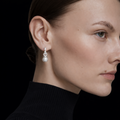 Boucles d’oreilles femme pendantes avec perle blanche et pierres brillantes en argent portées à l’oreille, style chic et raffiné